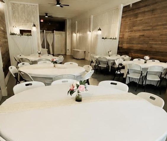 Round tables dressed in white linens with lace runners and pink roses